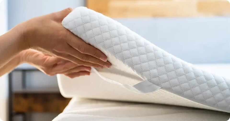 Person Placing Mattress Topper On Mattress